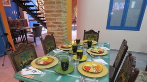 Zona de dinar amb taula verda preparada per l'esmorzar, incloent plats, tasses i coberts.