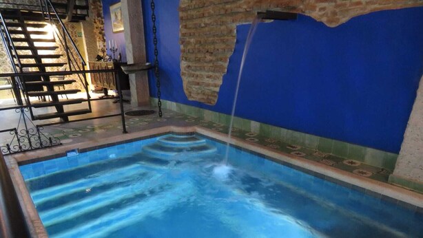 Una piscina amb una font d'aigua, una escala i una paret de maó.