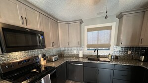 Una cocina moderna con microondas, tostadora, pileta y electrodomésticos de acero inoxidable.