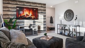 Een moderne woonkamer met een open haard, comfortabele zitmogelijkheden en een decoratieve klok aan de muur.