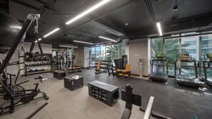 A gym with various exercise equipment, large windows, and a view of palm trees. - Apartment at Downtown Miami (Miami)