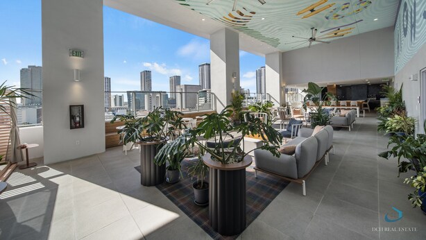 A spacious indoor area with modern furniture, potted plants, and a city view. - Apartment at Downtown Miami (Miami)