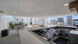A modern kitchen area with stainless steel appliances, a seating area with a sofa and chairs, and a view of the city through large windows. - Apartment at Downtown Miami (Miami)