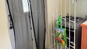 Una zona de cocina con estufa a gas, una parrilla metálica y una bolsa verde colgada de la parrilla.