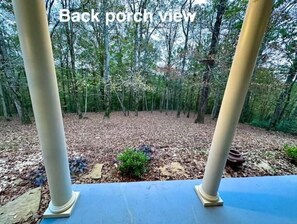 A back porch view with a wooden deck and a forested area in the background. - Serenity Retreat at Shenandoah (Dubach)