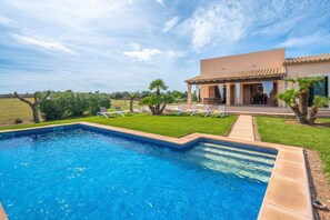 A swimming pool with a clear blue water surface, surrounded by a well-maintained lawn and a few palm trees. - Can Aina Finca in the nature for 6 with pool, ping pong, BBQ, Wi Fi (Son Serra de Marina)