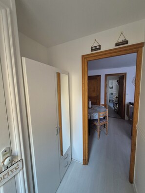 Een gang met een houten deurkozijn, een eettafel met stoelen en een zicht op een ruimte met een toilet en een wastafel.
