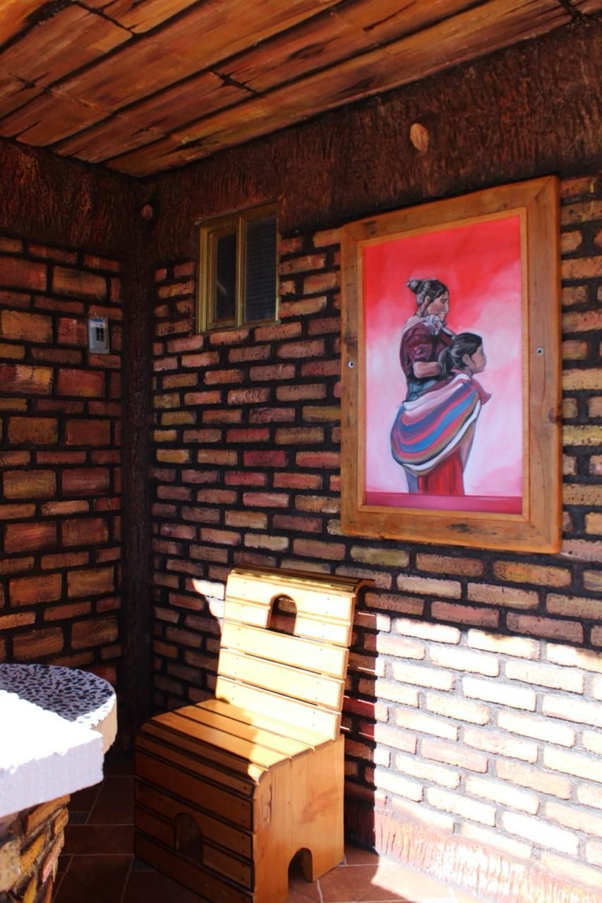 A rustic room with a brick wall, a wooden bench, a small table, and a framed painting.