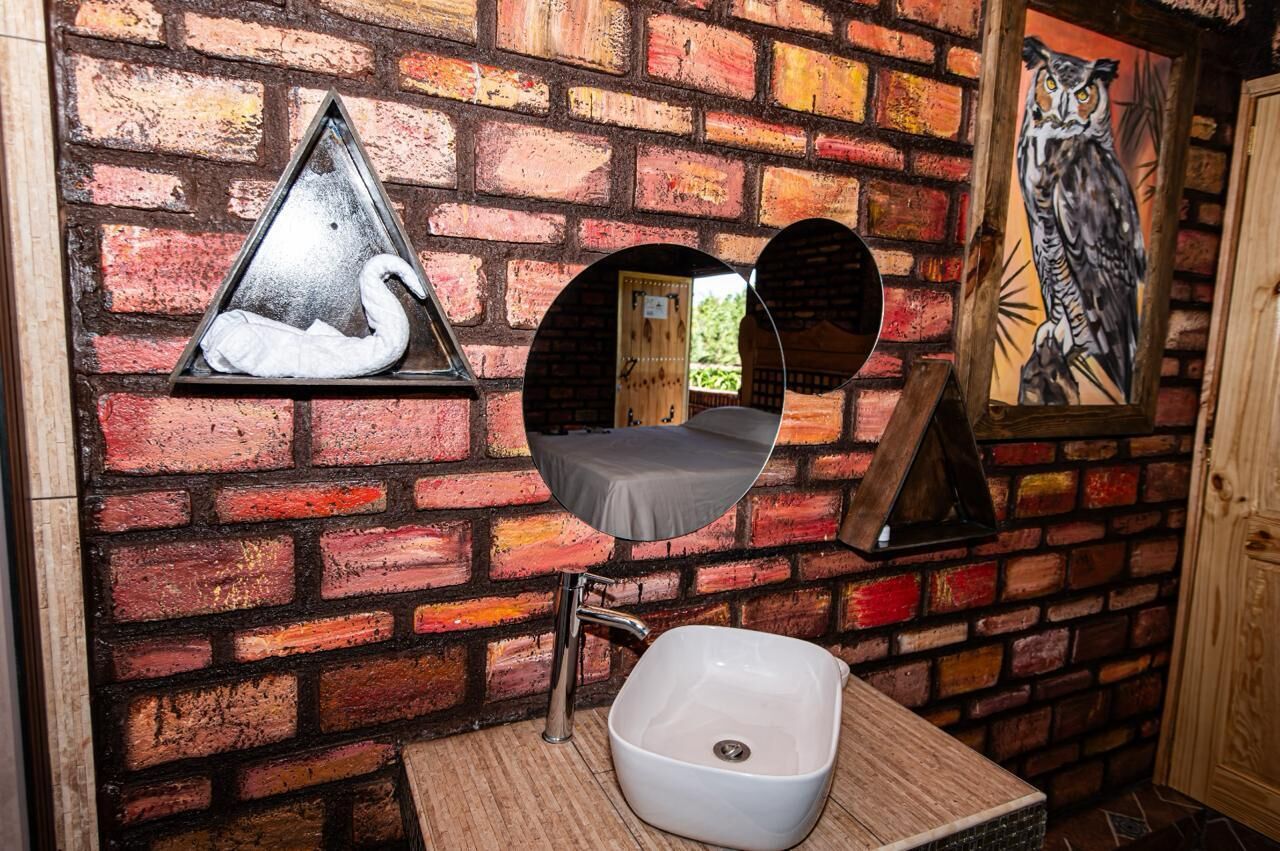 A bathroom with a white sink, a mirror, and a triangular wall decoration.