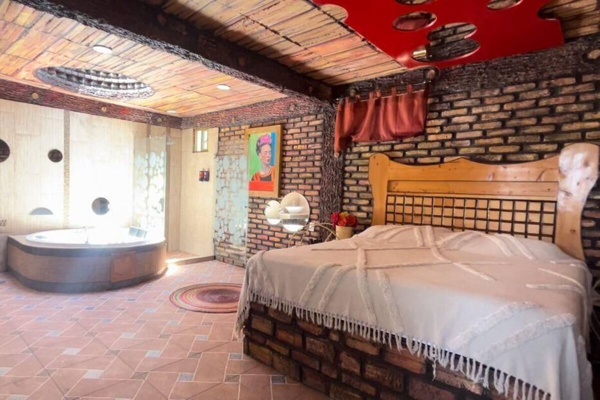 A room with a bed, a round bathtub, and a wooden headboard.