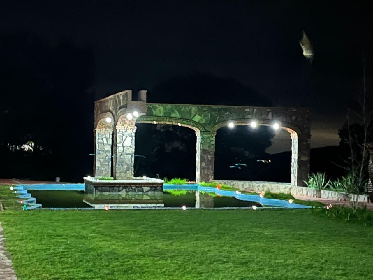 Un edificio de piedra con grandes ventanales arqueados y una fuente en primer plano.