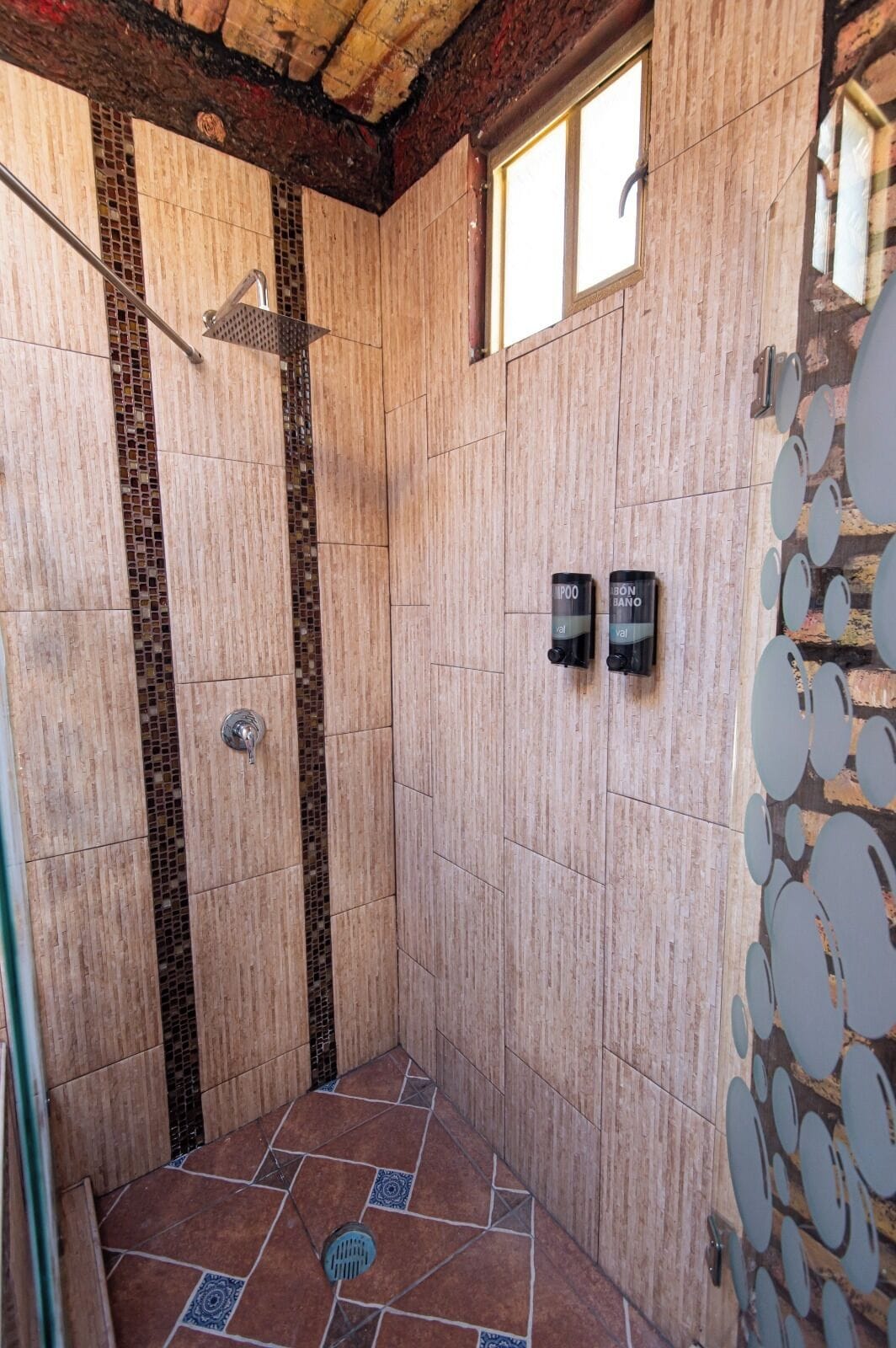 A shower area with tiled walls, a showerhead, and two wall-mounted hand dryers.