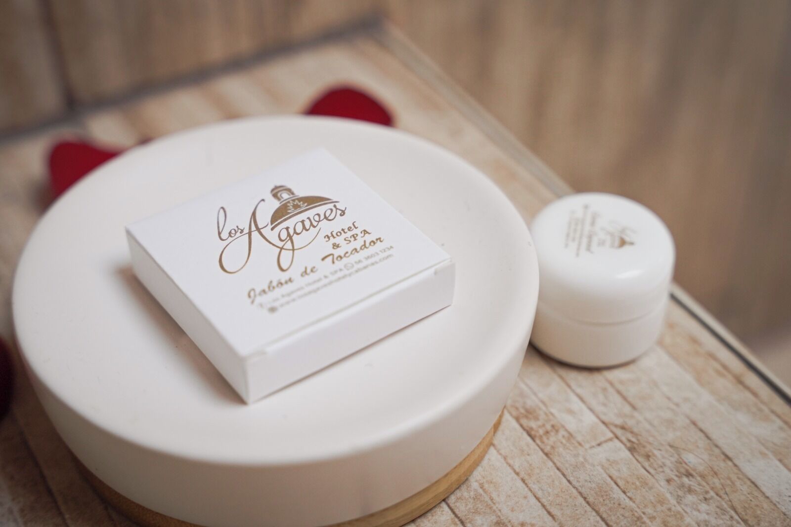 Una caja blanca con texto sobre una mesa redonda blanca, junto a un pequeño recipiente blanco.
