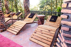 A terrace with wooden loungers, brick pillars, and a tiled floor.