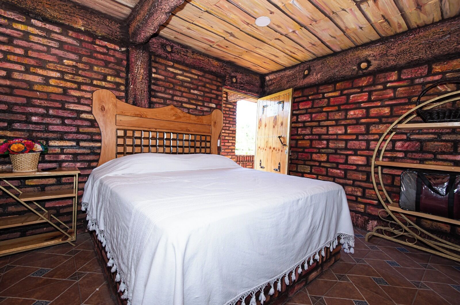 Ein rustikaler Raum mit einem hölzernen Bett, Ziegelwänden und einer Holzbalkendecke.