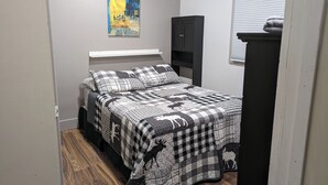 A bedroom with a bed, a painting on the wall, a wardrobe, and a window with blinds. - Small House in Downtown Wainwright (Wainwright)
