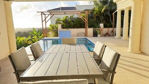 A poolside area with a table and chairs, a pergola, and a view of the surrounding landscape. - Feel like when you're at home.
12462311839 (All Regions)