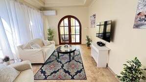 A living room with a sofa, coffee table, TV, and decorative plants. - Feel like when you're at home.
12462311839 (All Regions)