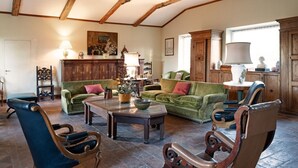 Ein gemütliches Wohnzimmer mit Holzbalken, grünen Sofas und Ledersesseln.