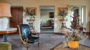 Eine geräumige Lobby mit Ledersessel, großem Tisch mit Lampe und zwei verzierten Vasen mit Trockenpflanzen.
