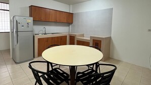 A compact kitchen with a refrigerator, sink, and wooden cabinets. There is a round table with four chairs. - Experience the Essence of Friendship: in the Heart of the Old Town (Phuket)