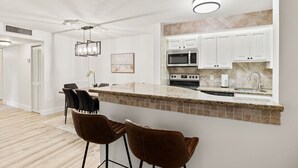 A modern kitchen with white cabinets, a granite countertop, and a built-in microwave. - Relaxing Three Bedroom in PGA National (Palm Beach Gardens)