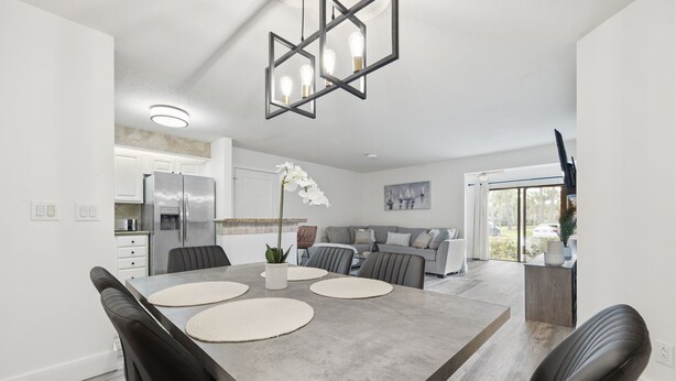 A modern kitchen with a built-in refrigerator, a dining area with a large table and chairs, and a living area with a sofa and a TV. - Relaxing Three Bedroom in PGA National (Palm Beach Gardens)