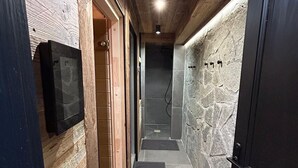 Un pasillo estrecho con paredes de madera, una pared de piedra y una puerta negra.