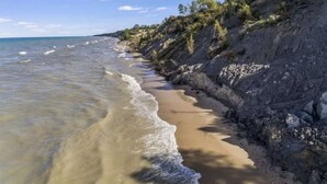 A beach with clear water, sandy shore, and rocky cliffs.