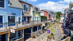 A row of colorful buildings with a covered walkway and outdoor seating areas.