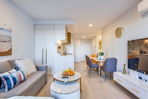 A modern apartment with a living room, dining area, and kitchenette.