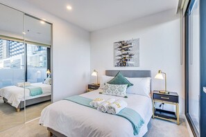 Ein modernes Hotelzimmer mit einem großen Bett, Nachttischen, einem Spiegel und Blick auf die Stadt.