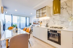 A modern kitchen with a built-in oven, a gas stove, and a marble backsplash.