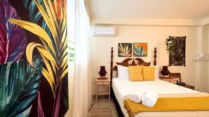 A hotel room with a bed, a nightstand, a lamp, and a wall-mounted air conditioner. - Boho Chic 2 bedroom - Miramar -1A (San Juan)