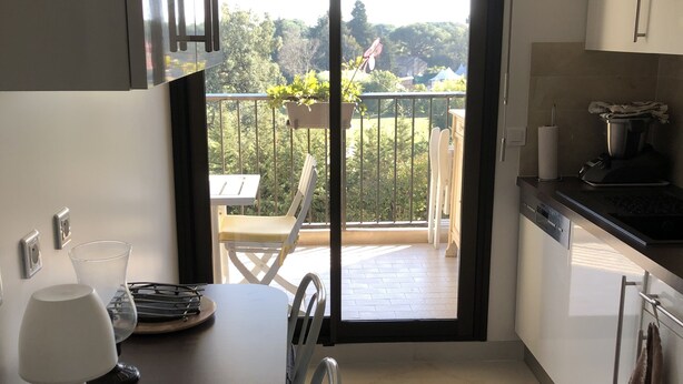 A modern kitchen with a dining area, a sliding glass door to a balcony, and a patterned floor.