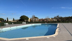 A rectangular swimming pool with a tiled deck, a ladder, and a bench.