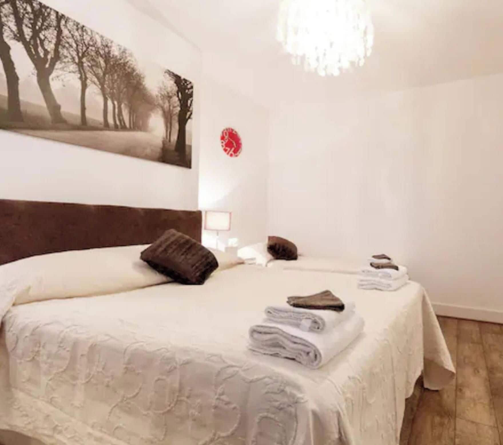 Une chambre à coucher avec un lit, une table de chevet, une lampe, un tableau et une horloge au mur.
