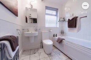 Un baño con lavamanos, inodoro y bañera blancos.