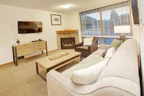 Relax in this inviting living room with a sofa, armchair, and stone fireplace.
