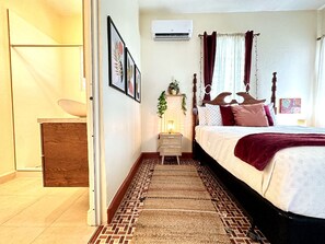 Quarto com cama, mesa de cabeceira, ar-condicionado fixado na parede e tapete estampado.