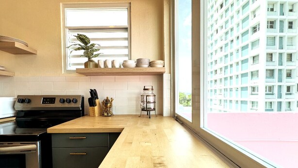 Una cocina moderna con encimera de madera, estufa integrada y ventana con vistas a un edificio.