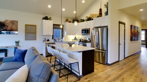 A modern kitchen with white cabinets, stainless steel appliances, and a central island with bar stools. - Pet-Friendly Bozeman Home ~ 7 Mi to Downtown! (Bozeman)