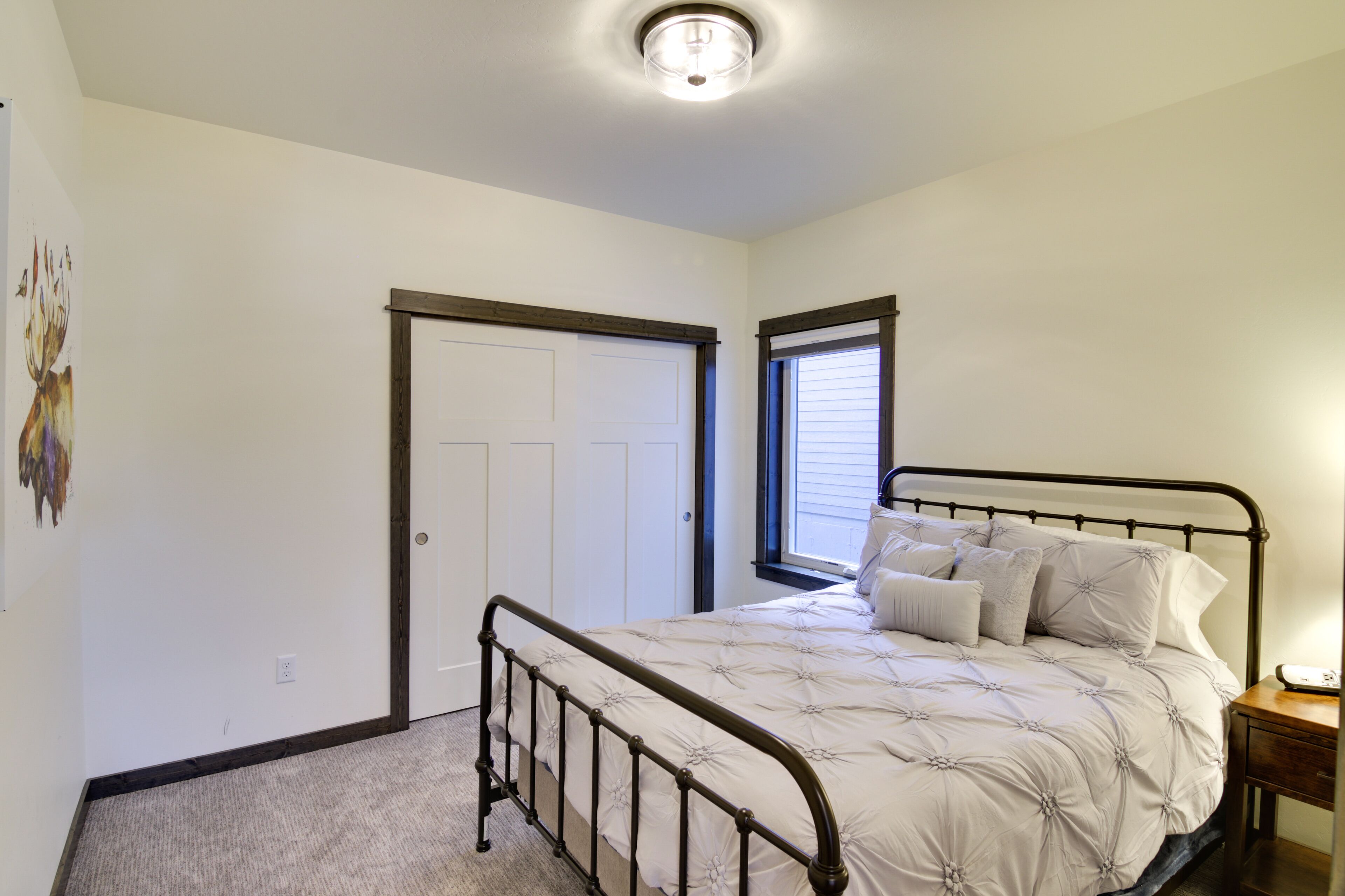 Une chambre à coucher avec un lit, une table de chevet, une porte et une fenêtre.