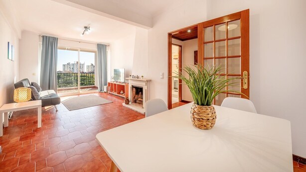 A spacious living room with a fireplace, a dining table, and a view of the city. - GuestReady - Charming stay with a terrace (Cascais)