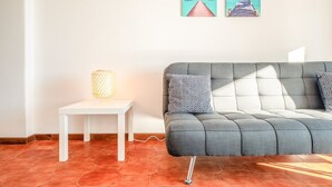 A modern living room with a grey sofa, patterned cushions, a white side table with a lamp, and two framed pictures on the wall. - GuestReady - Charming stay with a terrace (Cascais)