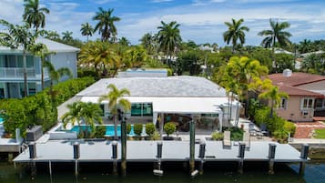 A waterfront property with a pool, dock, and surrounding palm trees.