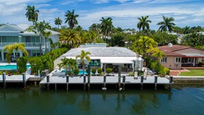 A waterfront property with a pool, dock, and multiple palm trees. - Casa Flamingo Intracoastal Heated Pool (Fort Lauderdale)