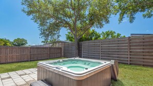 Ein Whirlpool in einem Garten mit Holzzaun und Baum.