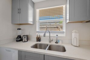A kitchen with a double sink, a toaster, a blender, a faucet, and a window with blinds. - Fully Fenced w/ Hot tub near Siesta Key Bridge! (Sarasota)