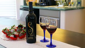 Una botella de vino y dos copas sobre una encimera de cocina.
